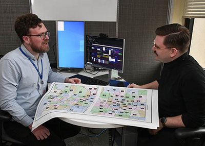 Two people sitting at a desk with a map of legislative districts between them.