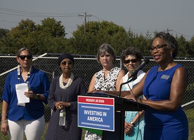 Met Council Vice Chair Reva Chamblis, right, welcomes speakers to an event at the Blue Lake Wastewater Treatment Plant announcing federal Climate Pollution Reduction grants. Other speakers included (left from the vice chair) Debra Shore, EPA Region 5 Administrator; U.S. Rep. Betty McCollum; U.S. Rep. Ilhan Omar; and Rebecca Ann Crooks-Stratton, Secretary/Treasurer of the Shakopee Mdewakanton Sioux Community. Woman at a podium flanked by four other women.