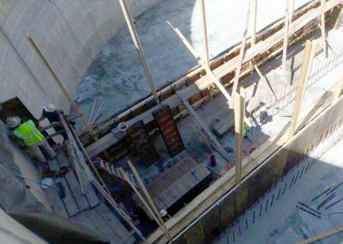 A circular building with lots of concrete and a small structure under construction.