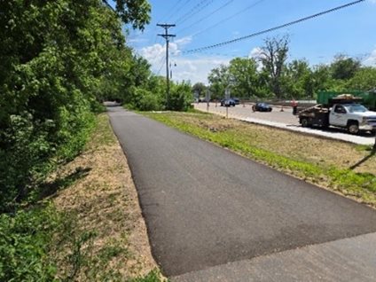 Photo looking down asphalt-paved path with grass on either side.