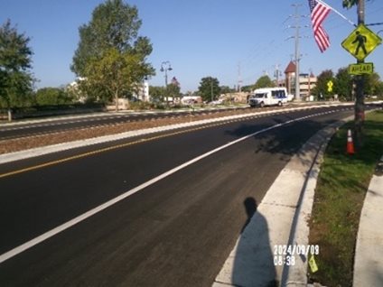 Photo of a newly-paved and striped road with new curb.