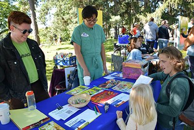 Woman and her child talk to two Met Council staff at the Imagine 2050 table at a community festival.