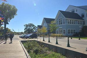 Two women walk along a lakeside boardwalk in front of Boatworks Commons, an apartment complex in White Bear Lake.