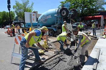 Workers apply cement at a transit station construction site.