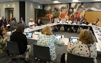 Two advisory council members address Met Council members, seated around a square of tables.