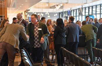 People shaking hands, picking up printed materials, talking with each other.