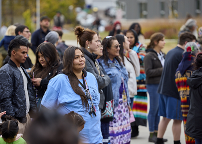 Indigenous people and others stand together in a crowd.