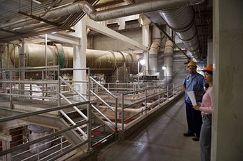 Two plant workers stand on an upper floor of the solids management building at the Metro Plant.